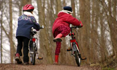 Børn cykler i efterårsskov