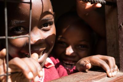 På billedet ses to skolepiger fra Uganda i et close-up. De kigger ind i kameraet og griner. 