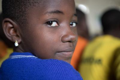 På billedet ses et close-up af en pige fra Uganda. Hun smiler ind i kameraet